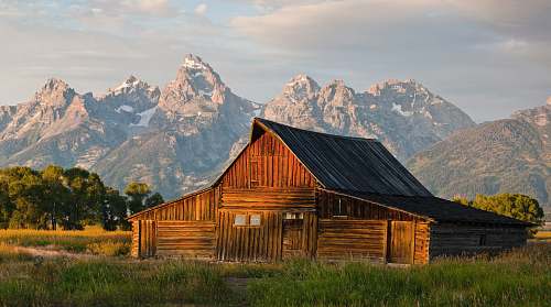 mormon row brown wooden house near brown mountain and green trees during daytime barn